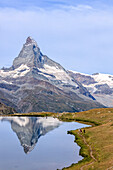 Hikers on the trail to the Matterhorn reflected in Lake Stellisee Zermatt Pennine Alps Canton of Valais Switzerland Europe