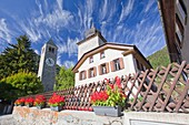 Flowers blooming by the church in Susch and unusual clouds up in the sky, Engadine, Switzerland Europe