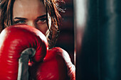 Close-up female boxer wearing punching gloves at gym