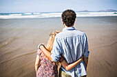 Rear view of loving couple standing arm around at beach