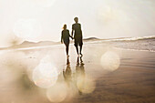 Full length of couple holding hands while walking at beach