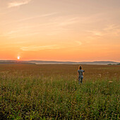 Caucasian woman walking in field at sunset