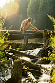 Caucasian woman sitting on log over waterfalls