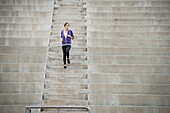Caucasian woman running on stadium staircase