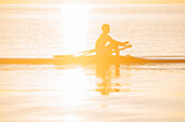 Silhouette of Caucasian man rowing on lake