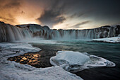 Gullfoss waterfall in northern Iceland at sunset in winter dress, as the falls are partly frozen