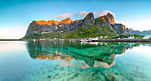 Panoramic of peaks reflected in clear water under the midnight sun Reine Nordland county Lofoten Islands Northern Norway Europe