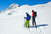 Two skiers on a ski tour on the Aebeni Flue firn fiel beneath the Mittagshorn peak, Loetschental, Valais, Switzerland.