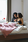 Woman kissing man while holding pie in bed at home
