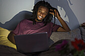 Happy man using laptop while sitting on sofa at home