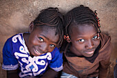Burkina Faso, Ouagadougou, Portraits of two girls with plaits leaning on a wall seen from above