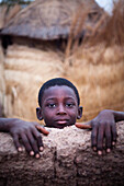 Burkina Faso, the village of Ponsom Tenga located 20 kilometers from Ouagadougou, 10-year-old child looking over a low wall