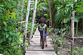 Brazil, Amapa, City of Fazendinha, Child playing by pushing a wheel on a wooden footbridge