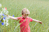 Junge auf einem Feld mit Kornblumen und Mohnblumen, Blumen pflücken bei Federow, MR,  Müritz-Nationalpark, Mecklenburgische Seen, Mecklenburgisches Seenland, Mecklenburgische Seenplatte, Mecklenburg-Vorpommern, Deutschland, Europa