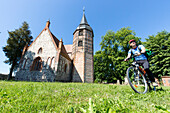 Cyclist, bicycle, cobblestone church in Galenbeck, MR, Mecklenburg lakes, Mecklenburg lake district, Mecklenburg-West Pomerania, Germany, Europe