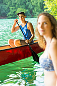 Canoing, girl and boy in red boat, women swimming, kayak, crystal clear green water, lake Schmaler Luzin, holiday, summer, swimming, MR, Feldberg, Mecklenburg lakes, Mecklenburg lake district, Mecklenburg-West Pomerania, Germany, Europe