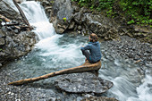 Junge Wanderin macht eine Pause an der Trettach auf dem Weg zur Kemtpener Hütte in den Alpen