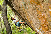 Male Climber Gets Ready To Latch The Next Hold On An Orange Granite Boulder