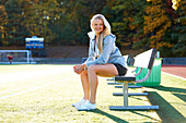 A Teenage Girl Sitting On The Bench At Soccer Field