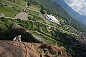 Mature woman ascends via ferrata, valley below