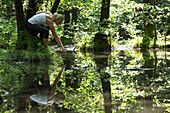 Woman touches surface of forest pond