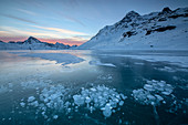 Ice bubbles frame the snowy peaks reflected in Lago Bianco, Bernina Pass, canton of Graubunden, Engadine, Switzerland, Europe