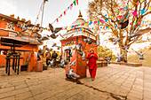 Woman walking and praying with pigeons at the hilltop temple, Bhaktapur, Kathmandu Valley, Nepal, Asia