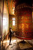 Woman praying at a Buddhist prayer wheel in Bouddha (Boudhanath) temple, UNESCO World Heritage Site, Kathmandu, Nepal, Asia