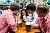 Young people in traditional cloth with beer mugs to toast at Oktoberfest, Munich, Bavaria, Germany