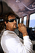 The captain of an expedition vessel talks on the radio in the wheel house.