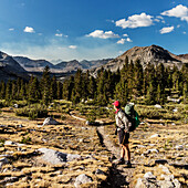 A female backpacker looking of her shoulder at the scenery while on the John Muir Trail in the Sierra Nevada, CA.