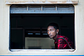 A young man waiting for the train to leave the station, Central Railway Station, Yangon, Myanmar.