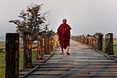 Buddhist Monk Walking On U Bein Bridge During Sunrise