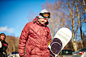 A Male Snowboarder Walking With His Board And Laughing