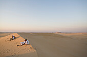 Locals and honeymooning Egyptians lounge at sunset on a sand dune near El-Siwa, one of Egypt's desert oases.