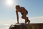 Woman Doing Exercise On Boulder Near Beach