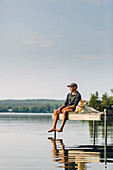 Man Enjoying View With His Dog On The Edge Of A Dock On Caspian Lake