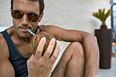 Close-up Of A Man Wearing Sunglasses Drinking Coconut From A Straw