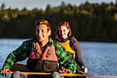 A Young Couple Paddles A Canoe Through Morning Mist On Long Pond, Greenville, Maine