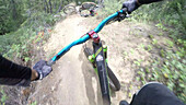 POV past hands of mountain biker on forest ride, friend crashes