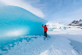 Fjallsarlon glacier lagoon, East Iceland, Iceland,  Man with red coat admiring the view of the frozen lagoon in winter , MR