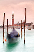 Europe, Italy, Veneto, Venice,  Gondolas tied up to wooden poles on the Canal Grande, in the background the monastery of San Giorgio Maggiore