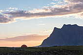 Der rosa Himmel um Mitternacht Sonne leuchtet das Zelt am Meer umgeben von felsigen Gipfeln Uttakleiv Lofoten Inseln Norwegen Europa