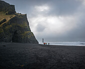 Strand von Reynisfjara, Vik, Sudurland, Island, Europa, Eine Gruppe von Fotografen geht auf den schwarzen Strand
