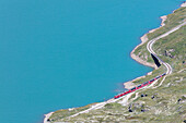 Der Bernina Express Zug fährt am Ufer des Lago Bianco Bernina Pass Kanton Graubünden Engadin Schweiz Europa