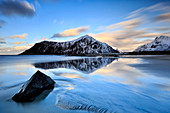 The icy waters of Flakstad Beach reflecting the snowy mountains, Lofoten Islands Skagsanden, Norway