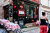 Woman walking down street passing by tipical restaurant terrace Saint Malo, Brittany, France