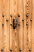Eine Hand aus Metall als Türklopfer an einer Holztür im Dorf, Valldemossa, Mallorca, Spanien