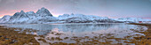 Panorama von rosa Himmel in der Morgendämmerung auf schneebedeckten Feldern und Holzhütte umgeben von gefrorenem Meer, Svensby, Lyngen Alpen, Troms, Norwegen, Skandinavien, Europa