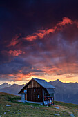 Hölzerne Hütte unter feurigem Himmel und Wolken bei Sonnenuntergang, Muottas Muragl, St. Moritz, Kanton Graubünden, Engadin, Schweiz, Europa